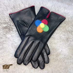 A pair of women's black Italian aniline leather gloves with a vibrant hand-stitched floral design on the back of each hand. The petals are rendered in blue, red, orange, green, and yellow leather, creating a joyful burst of color. The top cuff features a bold red piping trim.